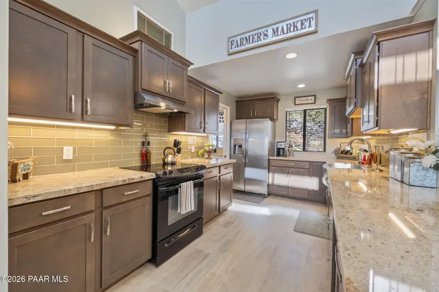 a open kitchen with stainless steel appliances granite countertop a stove top oven a dining table and chairs with wooden floor