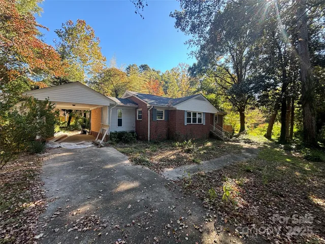 a view of a yard in front of a house with large trees