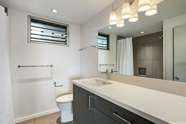 a bathroom with a sink a toilet a mirror and shower