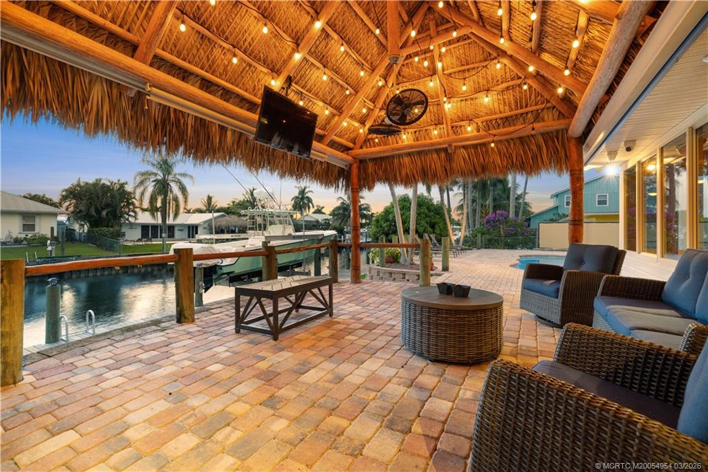 1359 Southwest Dyer Point Road Palm City, FL 34990 - Photo 4 of 55 a view of a patio with a dining table and chairs with wooden floor