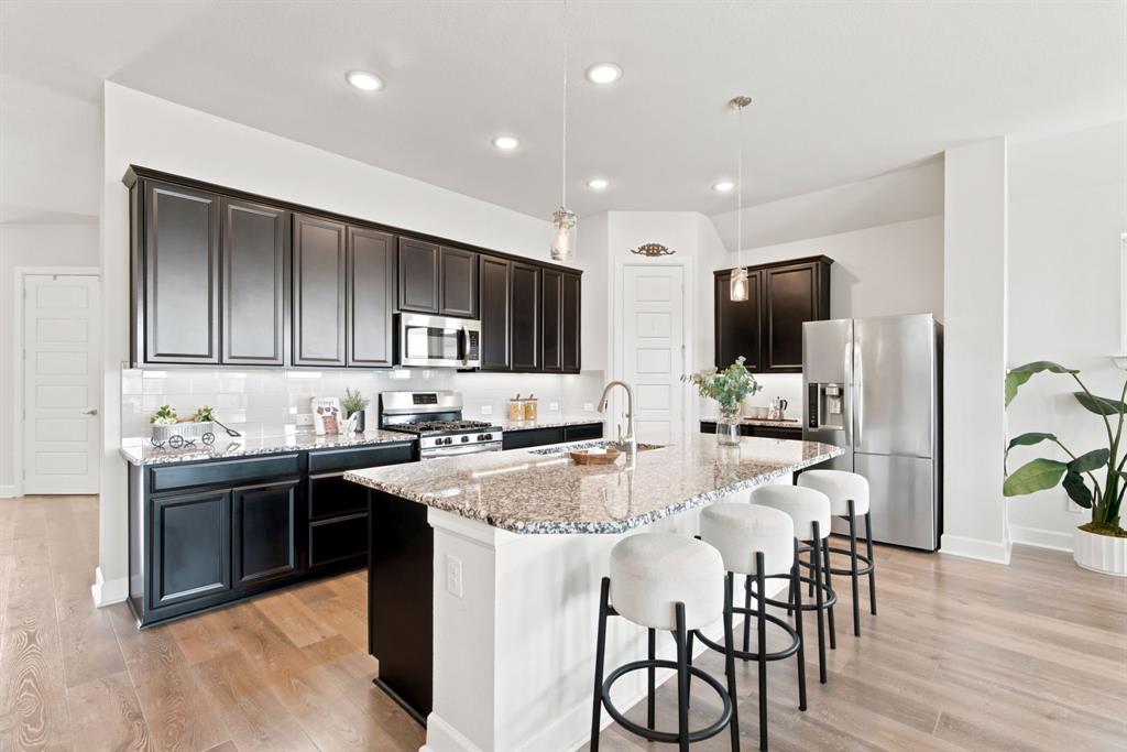 709 Bent Brook Road Oak Point, TX 75068 - Photo 9 of 27 Spacious kitchen with a central island, dark wood-finish cabinetry, stainless steel appliances, and wood-finish flooring