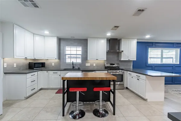 a kitchen with stainless steel appliances a sink a stove a refrigerator cabinets and a dining table