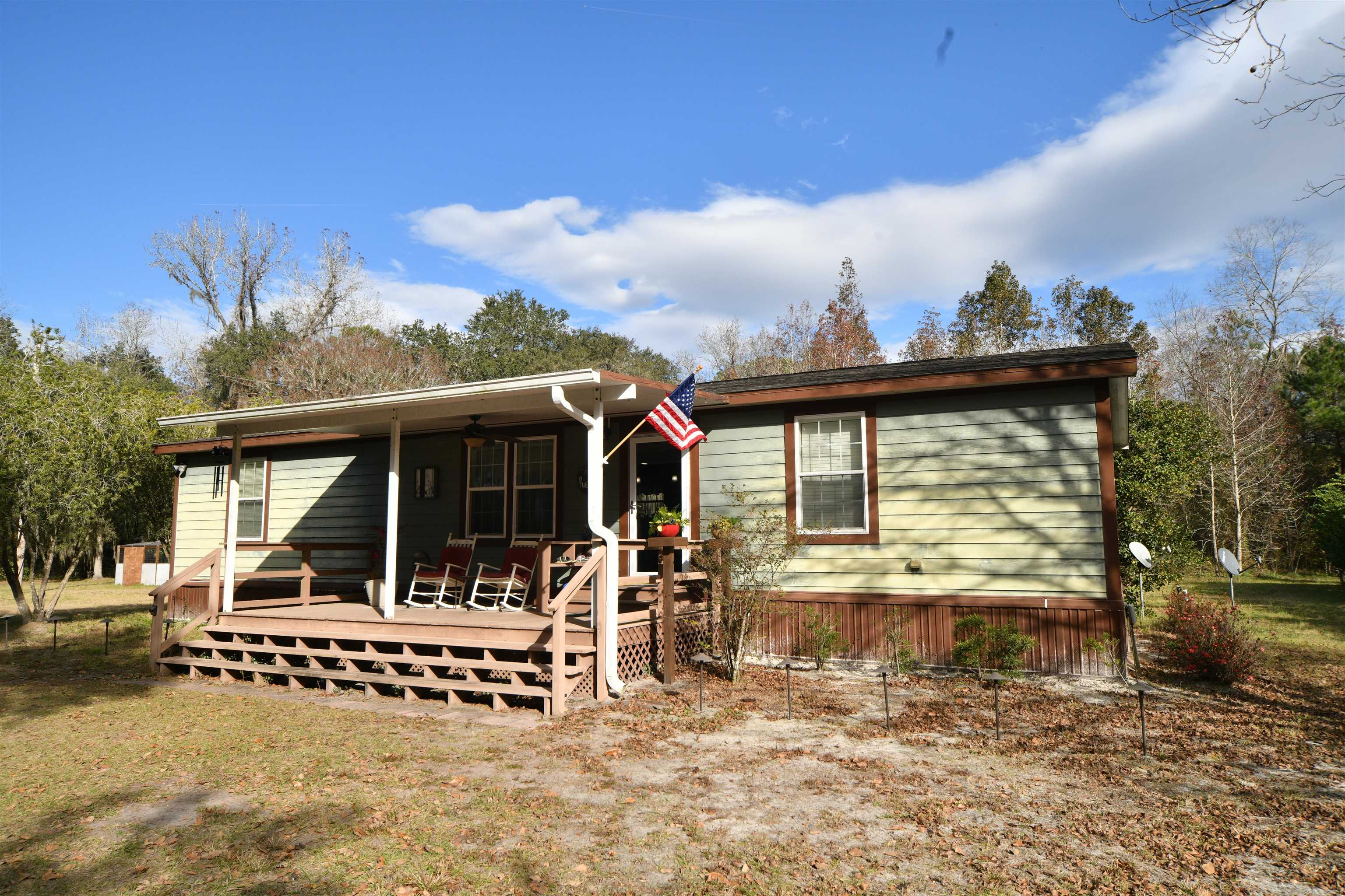 View of front facade with ceiling fan and a wooden deck