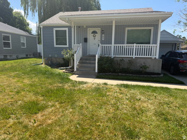 Exterior featuring light blue horizontal siding, a covered porch with white railings, a concrete walkway, and an attached garage