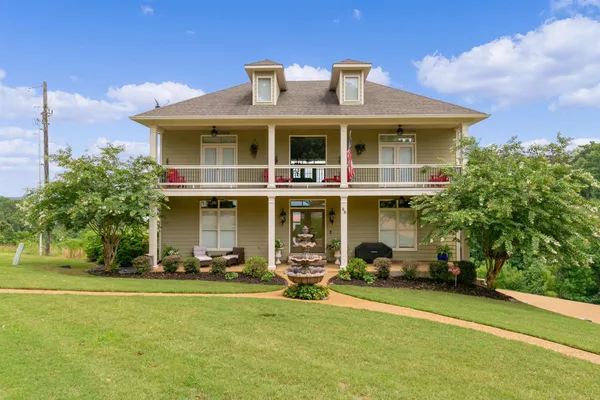 a front view of a house with a garden and trees
