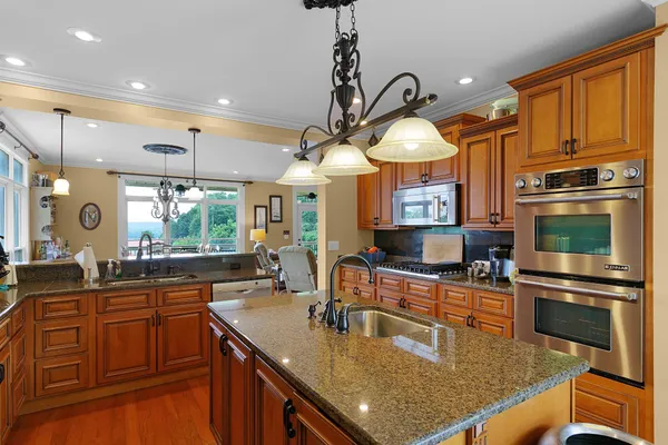a kitchen with stainless steel appliances granite countertop a sink a stove and a refrigerator