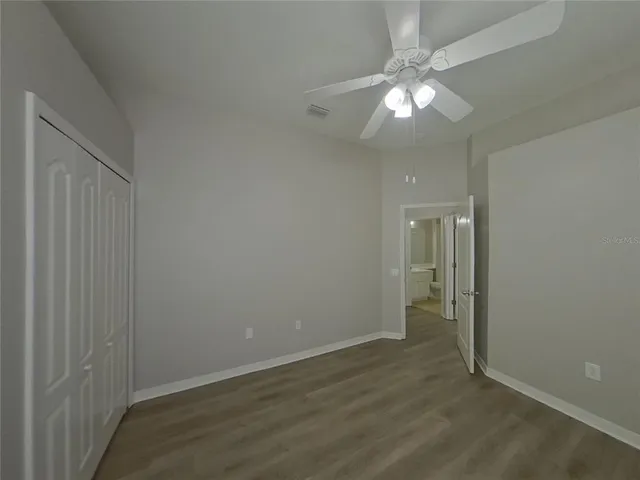an empty room with wooden floor and chandelier fan