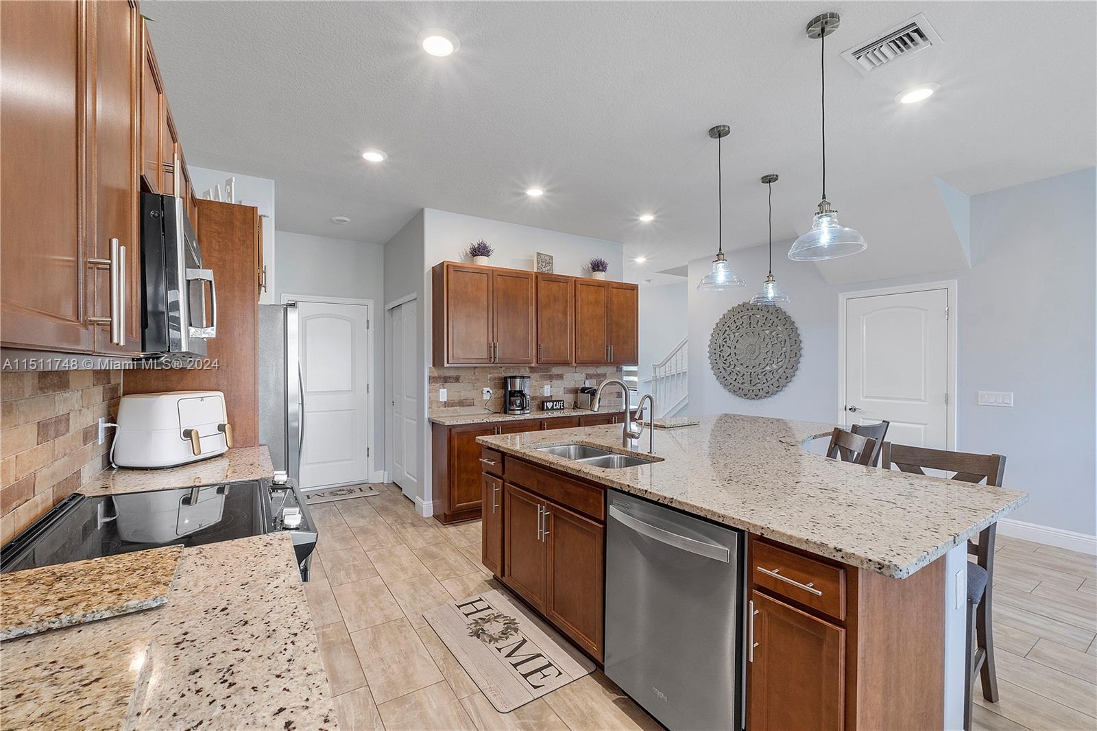 8339 Cadre Noir Road Lake Worth, FL 33467 - Photo 37 of 44 a kitchen with stainless steel appliances granite countertop a sink a stove and a wooden floors