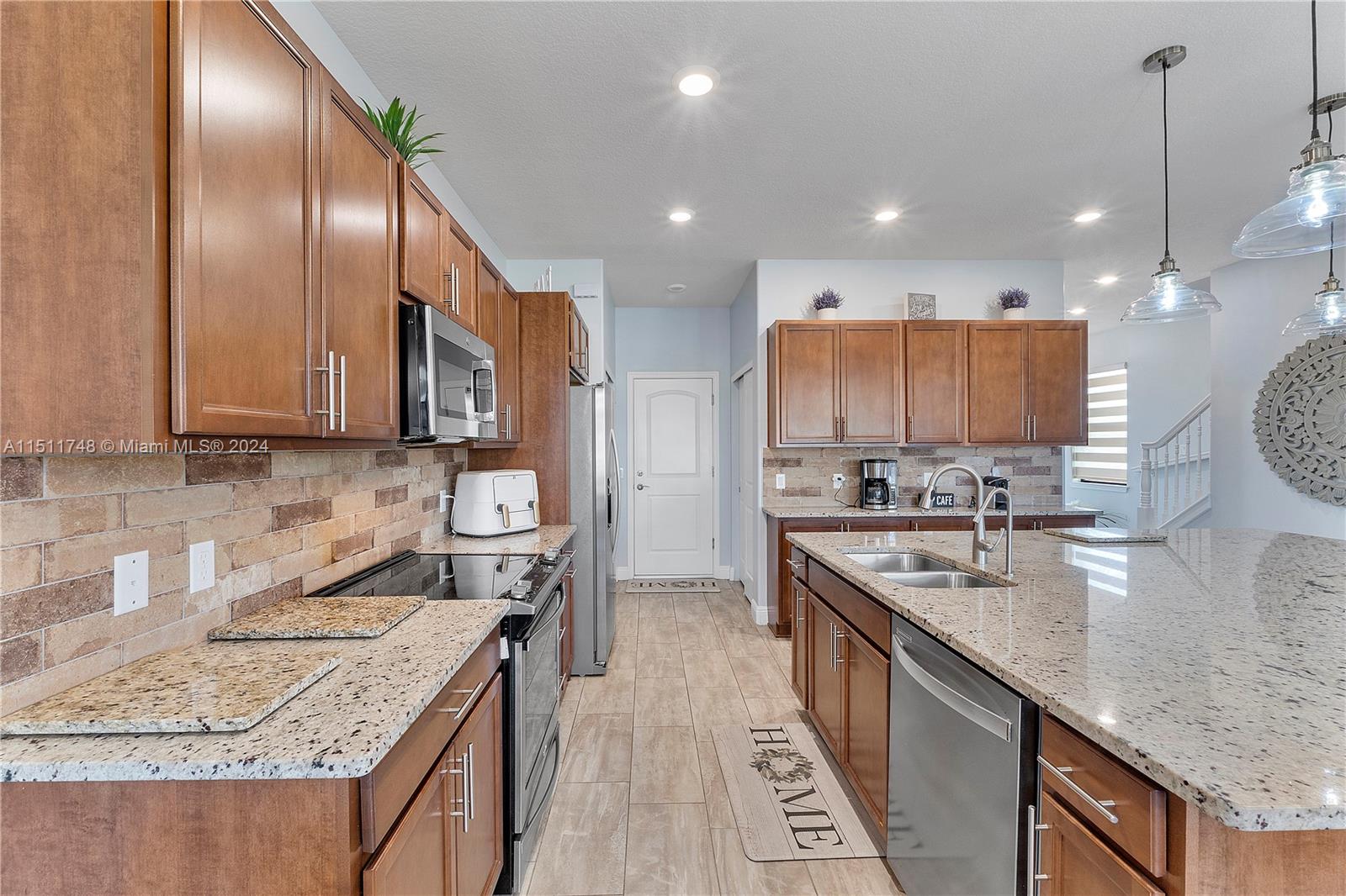 8339 Cadre Noir Road Lake Worth, FL 33467 - Photo 38 of 44 a large kitchen with stainless steel appliances granite countertop plenty wooden cabinets counter space a sink and wooden floor