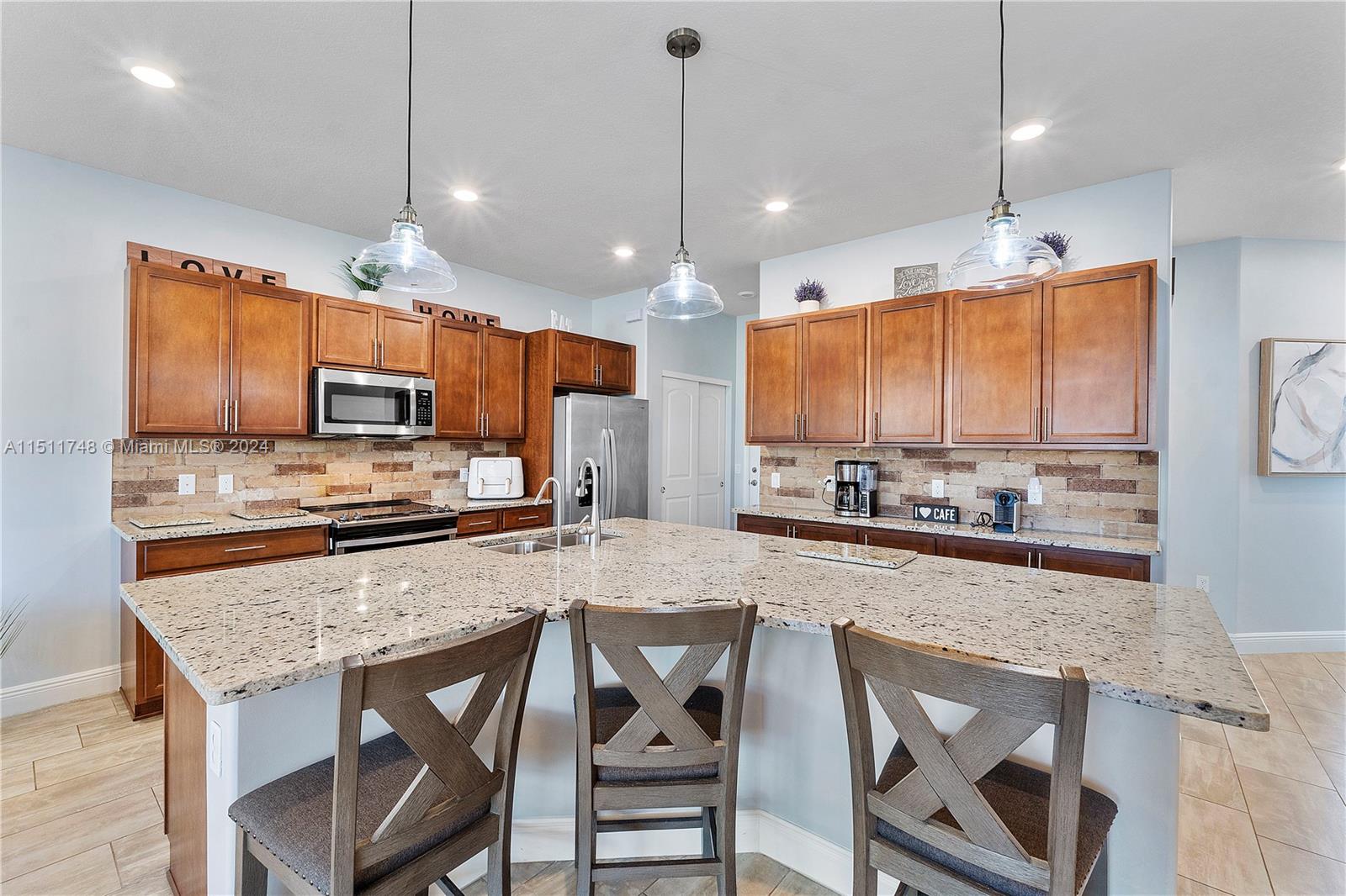 8339 Cadre Noir Road Lake Worth, FL 33467 - Photo 39 of 44 a kitchen with stainless steel appliances granite countertop wooden cabinets a stove a sink and a refrigerator