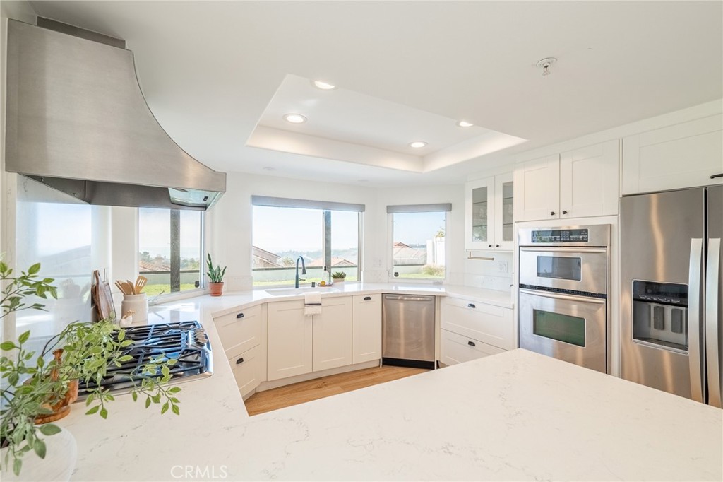 27 Burriana San Clemente, CA 92672 - Photo 21 of 66 a large white kitchen with a stove a refrigerator a sink dishwasher with a dining table and chairs