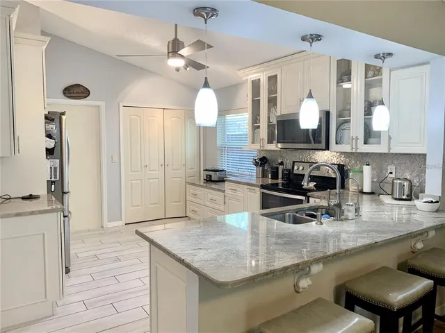 a kitchen with stainless steel appliances granite countertop a sink refrigerator and cabinets