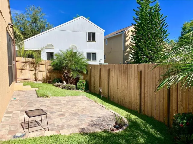 a view of a white house next to a yard with plants and trees