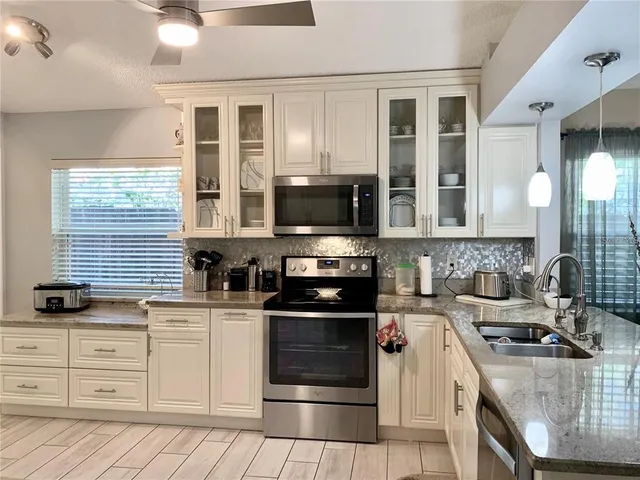 a kitchen with granite countertop a stove sink and microwave