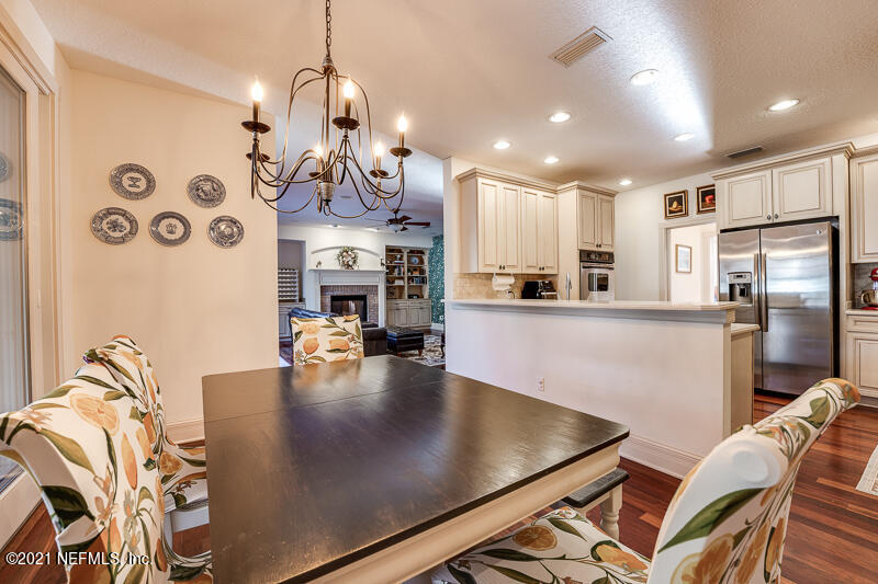 2710 Holly Point Road East Orange Park, FL 32073 - Photo 20 of 64 a kitchen with stainless steel appliances kitchen island granite countertop a refrigerator a stove a sink dishwasher and a dining table with wooden floor