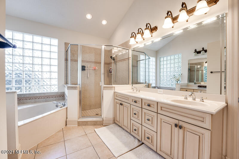 2710 Holly Point Road East Orange Park, FL 32073 - Photo 34 of 64 a spacious bathroom with a double vanity sink a large mirror a bathtub and next to a window