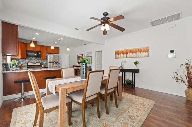 a kitchen with stainless steel appliances granite countertop a refrigerator a sink dishwasher a stove and a dining table with wooden floor