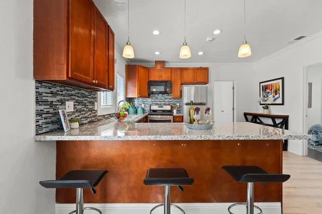 a kitchen with stainless steel appliances granite countertop a refrigerator a stove and a sink