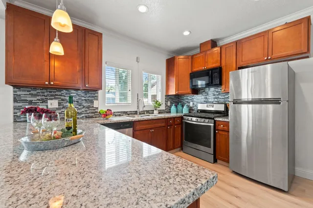 a room with kitchen island stainless steel appliances sink cabinets and wooden floor