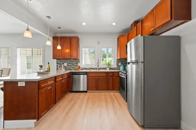 a kitchen with stainless steel appliances granite countertop a stove top oven a refrigerator and a microwave oven