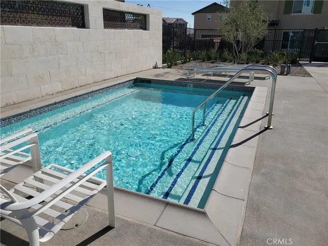 a view of swimming pool with lawn chairs and plants
