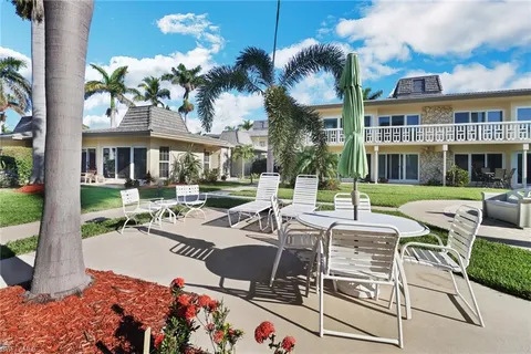 a view of a patio with couches table and chairs potted plants and palm trees