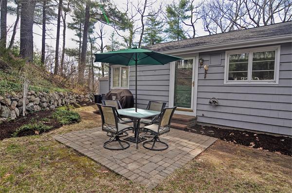 272 Main Street Norfolk, MA 02056 - Photo 26 of 29 a view of a patio with table and chairs under an umbrella with large trees