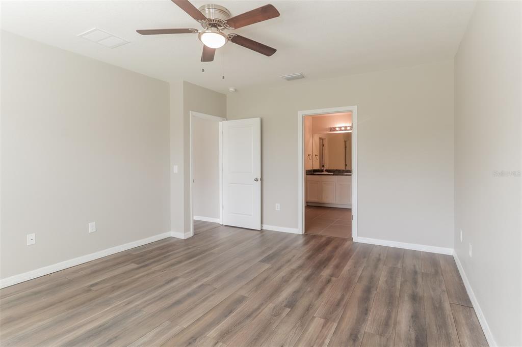 13628 Covey Run Place Spring Hill, FL 34609 - Photo 11 of 22 an empty room with wooden floor and way to kitchen