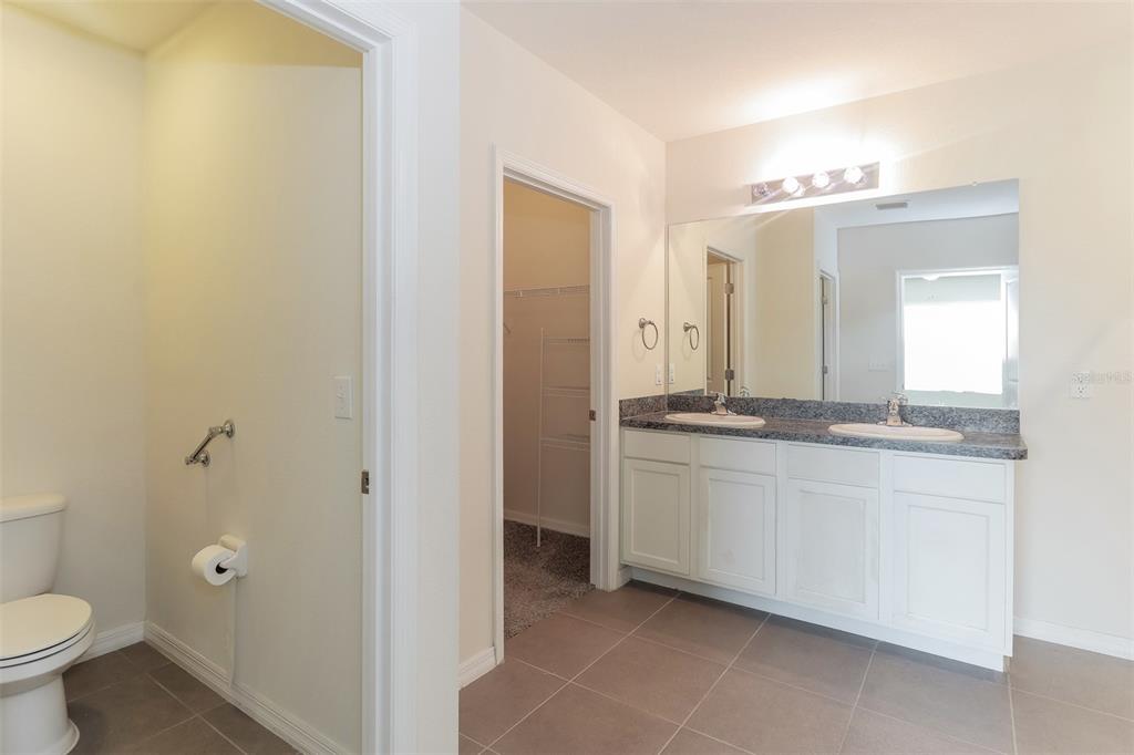 13628 Covey Run Place Spring Hill, FL 34609 - Photo 12 of 22 a bathroom with a granite countertop sink a toilet and a mirror