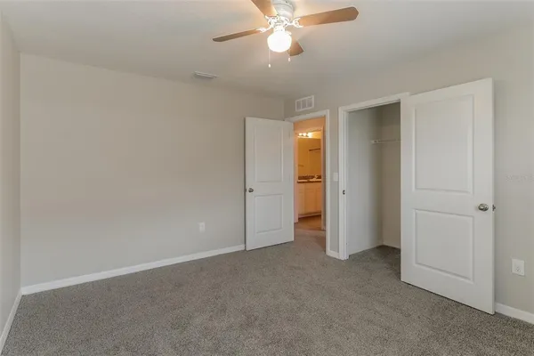 an empty room with closet and a ceiling fan