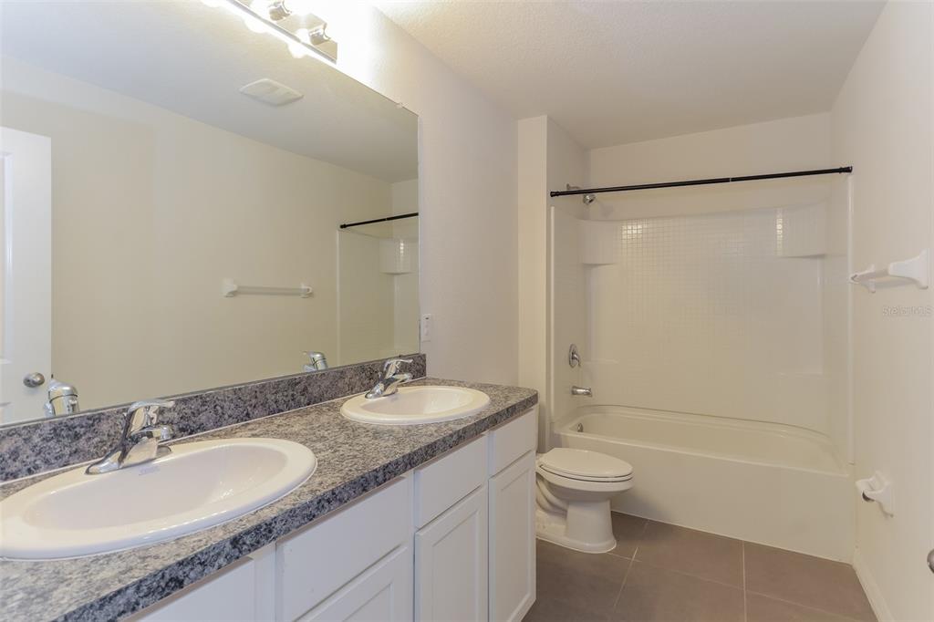 13628 Covey Run Place Spring Hill, FL 34609 - Photo 19 of 22 a bathroom with a granite countertop sink toilet mirror and shower