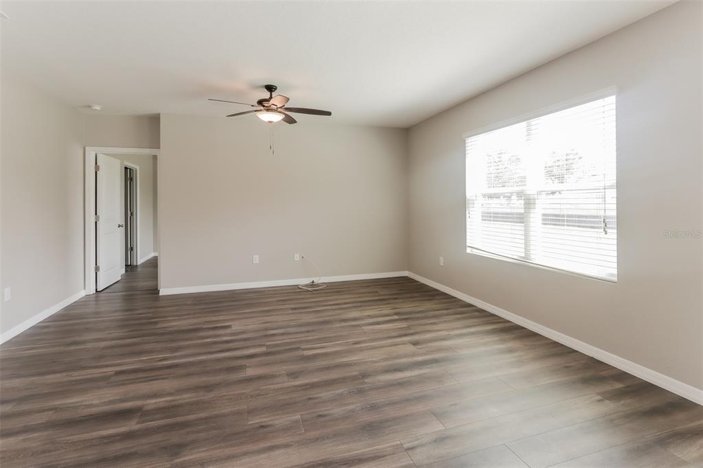 13628 Covey Run Place Spring Hill, FL 34609 - Photo 3 of 22 an empty room with wooden floor ceiling fan and windows