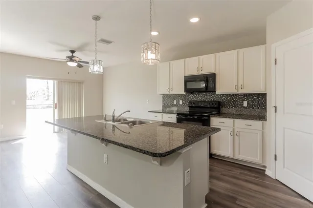 a kitchen with granite countertop a sink a counter top space appliances and cabinets
