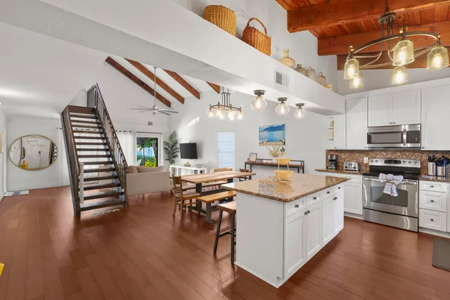 a kitchen with stainless steel appliances kitchen island granite countertop a sink cabinets and wooden floor