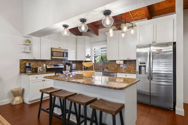 a kitchen with stainless steel appliances granite countertop a sink a stove a refrigerator cabinets and chairs