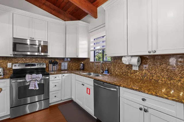 a kitchen with stainless steel appliances granite countertop a stove a sink and white cabinets