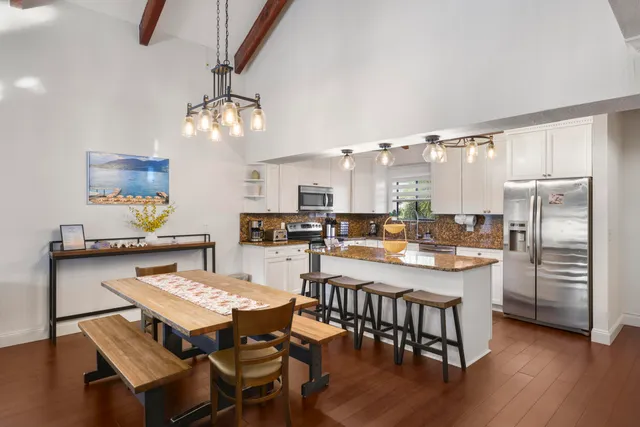 a kitchen with a dining table chairs stainless steel appliances and cabinets
