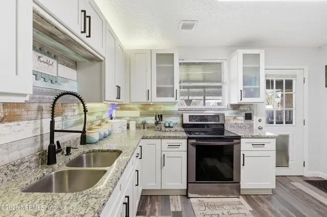 a kitchen with granite countertop a sink stainless steel appliances and cabinets