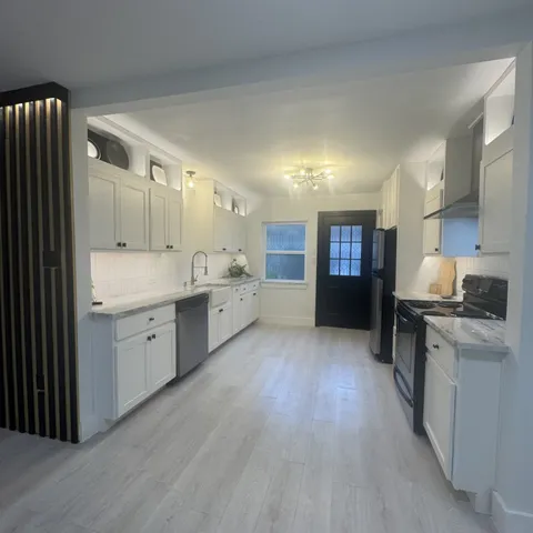 a large kitchen with a lot of counter space and wooden floor