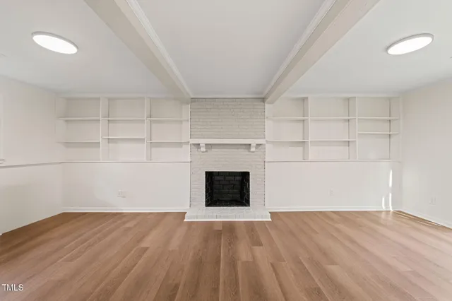 a view of empty room with wooden floor and fireplace