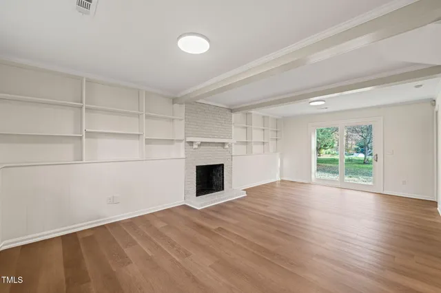 a view of empty room with wooden floor and fireplace