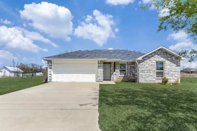a view of a yard in front of a house with a large tree