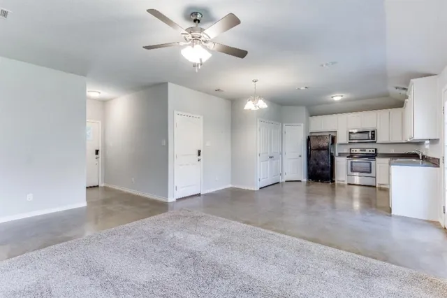 a view of a kitchen with a stove cabinets a ceiling fan and wooden floor