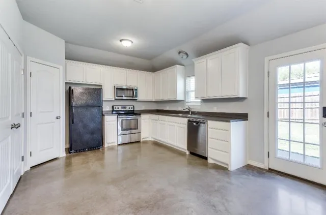 a kitchen with granite countertop white cabinets and stainless steel appliances