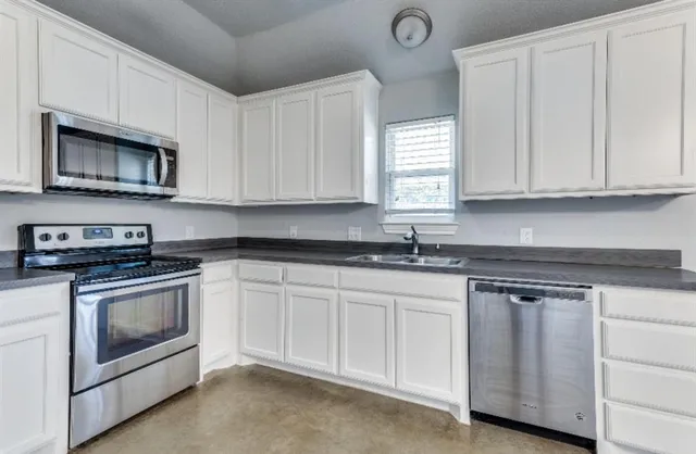 a kitchen with granite countertop white cabinets and stainless steel appliances
