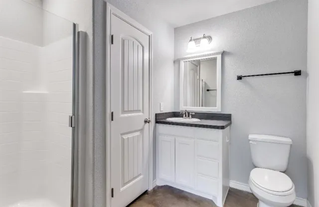 a bathroom with a granite countertop sink a toilet and a mirror