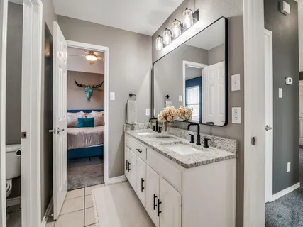a en suite bathroom with a granite countertop sink and a mirror