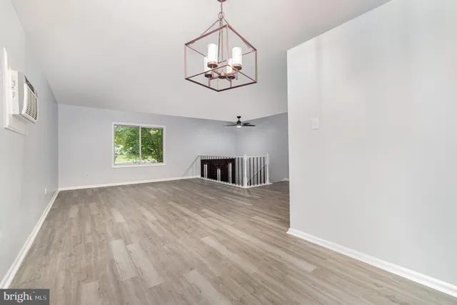 an empty room with wooden floor a chandelier fan and windows