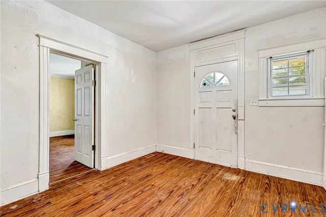 an empty room with wooden floor mirror and windows