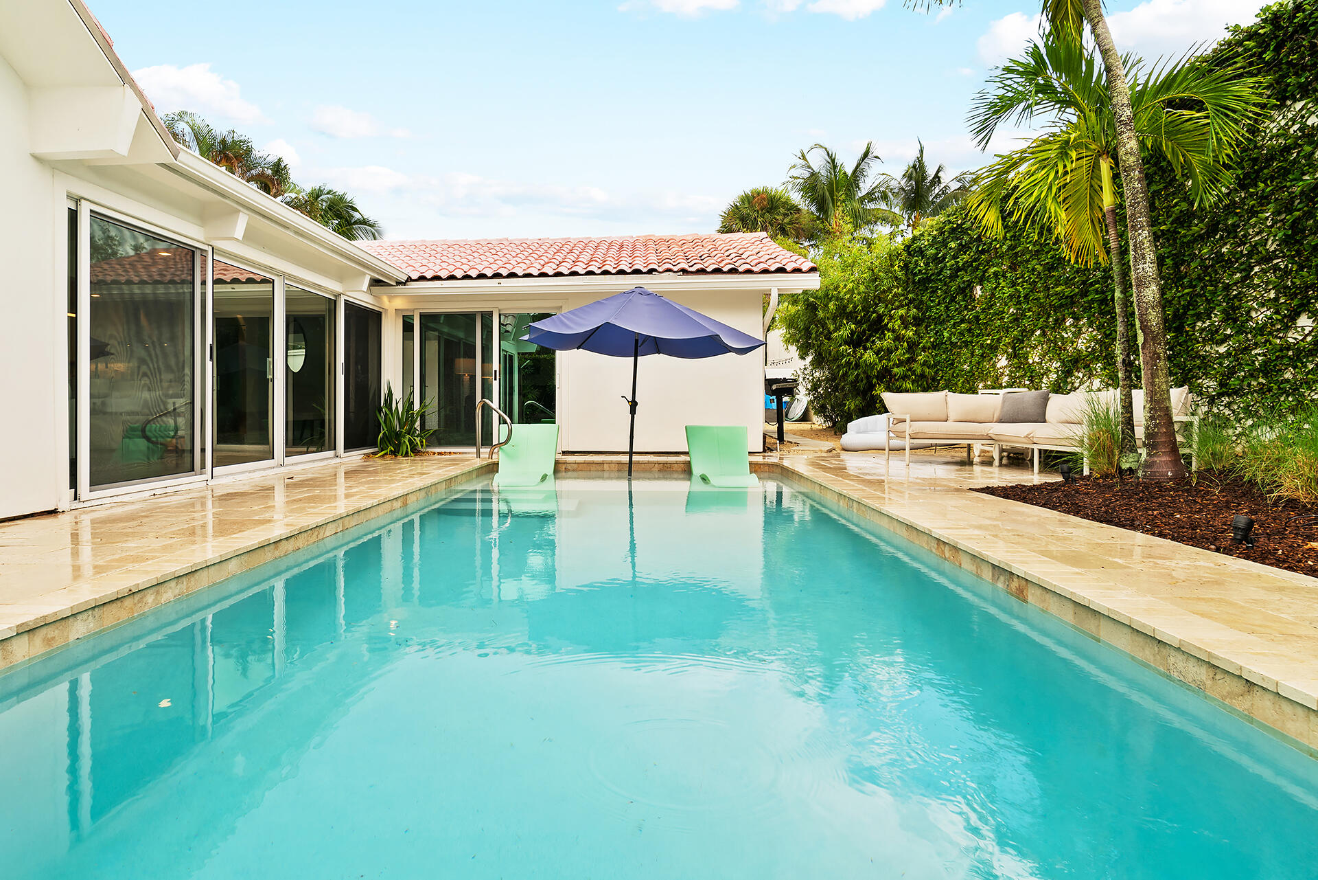 Undisclosed Address Jupiter, FL 33477 - Photo 38 of 107 a view of a patio with a table and chairs under an umbrella with large trees
